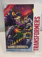 Front box art featuring Dinobot characters in battle scene and branding details