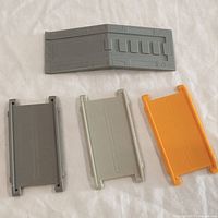 Four assorted plastic parts laid out on white cloth background, showing front and back surfaces