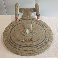 Top-down photo of the USS Enterprise NCC-1701-D scale model showing the saucer section with detailed markings and twin warp nacelles attached, red accents on nacelles visible.