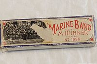 Box lid showing text 'Marine Band Made by M. Hohner Germany No. 1896' and vintage graphics