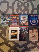 Photo of 7 DVDs spread out on patterned fabric showing titles: Top Gear 12, Tostitos Moises State, An American Tail Fievel Goes West, FIFA Fever, U-571, Hamburger Hill, and Fahrenheit 9/11.