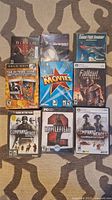 Photo showing 7 PC game cases arranged on carpet, featuring Diablo II, Fallout New Vegas, Company of Heroes (two versions), Battlefield 2, Supreme Commander, Combat Flight Simulator, and The Movies.
