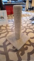 Lightly used beige carpet cat scratching post with square base and vertical post