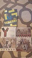 Photo showing front covers of Y The Last Man, Tetris, and Crossed comic books laid out on a carpet.