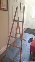 Full view of the wooden easel from the front showing the adjustable crossbars and frame design.