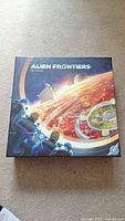 Photo of Alien Frontiers board game box with outer space and planetary colony artwork