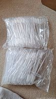 Two ziplock plastic bags filled with clear plastic 1ml pipettes, laid on a carpeted floor.