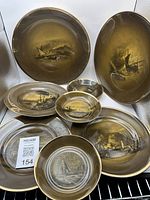 Overview of 9 plates showing designs and shapes including round and oval plates with nautical scenes in brown and gold tones.