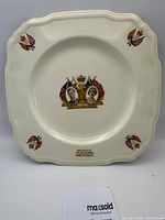 Front view of the white porcelain plate with decorated images and British flags.