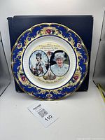 Photo showing the full commemorative plate with box behind it and MaxSold lot number card in front.