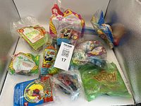 Photo showing multiple McDonald's Happy Meal toys sealed in original packaging with diverse themes including The Beach Planet.