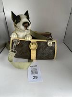 Front view of the medium-sized brown textured purse with detailed resin dog sculpture on top, showing the purse front buckle and pale green adjustable strap.