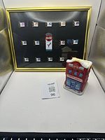 Full view of the Coca-Cola framed pins set and miniature ceramic building shown together
