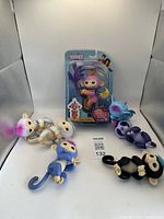 Seven Fingerlings figures: six interactive monsters with multiple colors and one Baby Monkey in original packaging with pink color and orange hair.