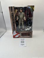 Front view of the Ghostbusters Trevor action figure in packaging, showing figure and included accessories such as ghost trap and proton pack.