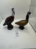 Photo showing turkey and goose glass bird decanters and figurines on white background, highlighting detailed glass textures and colors.
