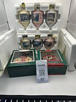 Six Hallmark Christmas ornaments in white protective styrofoam packaging with original boxes beneath.