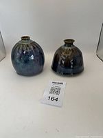 Photo of two multicolor glazed ceramic vases side by side on white background showing shape and color variations.