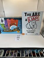 Two boxed party card games set side by side, Dan Ariely's Irrational Game with colorful box and You Are A Liar in white box with graphic design.