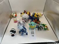 Overview photo showing the full set of Pokemon vinyl figures including Squirtle, Eevee, Meowth, Dialga, Palkia, and others on a white background with identification number.