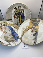 Three porcelain decorative plates with cultural and traditional scene designs, multicolor and gold accents, artist signed