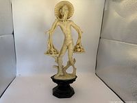 Front view of the resin Oriental farmer statue standing on a black hexagonal base showing the intricate details of the hat, pole, baskets, and figure.