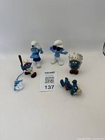 Photo showing all six Smurf figurines arranged individually on a white background with auction card visible.