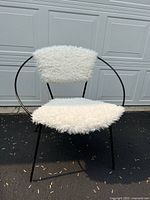 Front view of the vintage 1950s hoop chair showing circular black wrought iron frame and white fluffy upholstery on seat and backrest.
