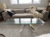 Front view showing glass top over lucite cantilever base in living room setting