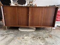 Front view showing overall design, sliding doors, and brass legs.