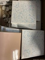 Close-up of 4.25” square ceramic tiles with blue floral pattern and pastel pink tiles stacked together.