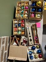 Overview of multiple boxes containing assorted vintage glass ornaments, tree topper and crystal drops