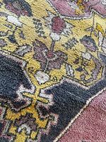 Close-up of the rug pile and pattern showing intricate floral and geometric design with visible moth damage.