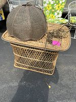Rattan dome-shaped pendant lamp placed on rattan side table, showing woven patterns and attached power cord with plug.