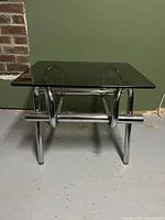 Front view of table showing chrome tubular base and smoked glass top