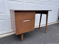 Front angled view showing desk top, left-side drawers and tapered legs