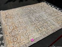 Overhead view of full rug laid on asphalt showing overall pattern and condition