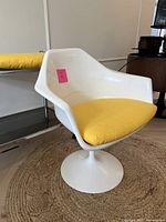 Front-left three-quarter view of white tulip armchair with yellow cushion