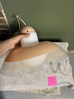 Side view of pink pendant lamp showing dome-shaped shade with fine white lines on clear glass ring.
