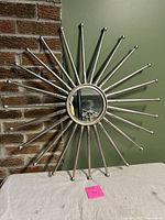 Front view of full starburst frame with central mirror against green wall