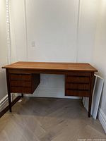 Front view of entire teak desk showing overall form and tapered legs