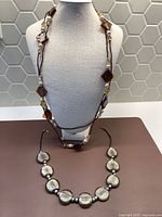 Displayed on a mannequin, both necklaces laid flat showing length and bead shapes.