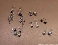 Full lot view with five pairs of vintage-style earrings on brown background.