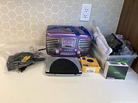 Lot showing vintage-inspired Citizen radio, silver media player, assorted electronics cables, and unopened accessories