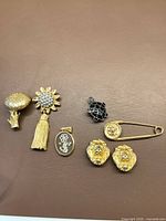 Top view of the seven jewelry pieces including the gold-tone brooches, clip-on earrings, and silver turtle pendant.