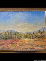 Full view of the signed acrylic landscape painting showing blue sky with clouds, trees, and field in warm colors, framed in a bright gold wooden frame with beaded edge.