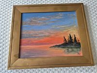 Frontal view of the signed sunset acrylic painting on canvas showing the wooden bright gold frame with minor wear.