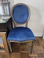 Full front view of the vintage chair showing blue velvet seat and oval backrest with wooden frame.