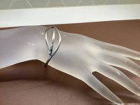 Front angled view of the sterling silver bracelet on a display hand, showing the open design with two elongated overlapped ovals.