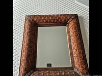 Front view of the vintage wall mirror showing wooden basket weave patterned frame and reflective surface.
